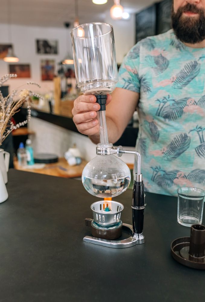 Barista skillfully preparing specialty coffee using Japanese siphon