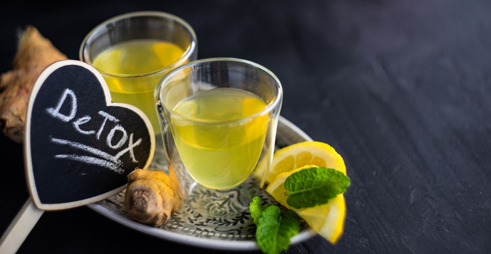 Two yellow detox drinks with ginger and lemon