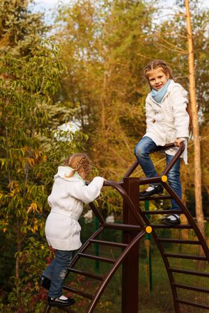 Two young girls climbing playground stairs in park