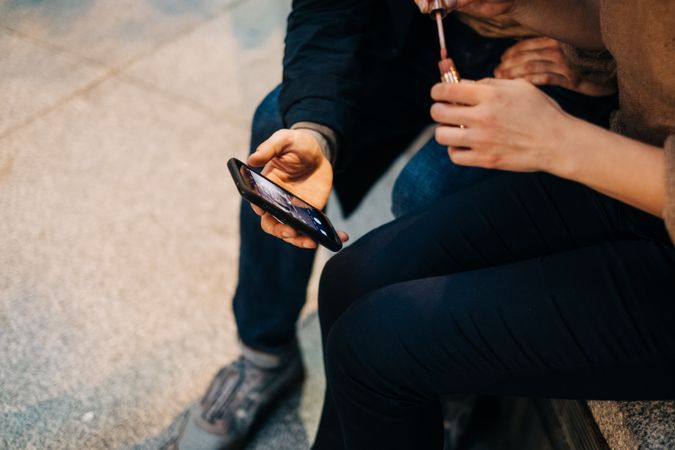 Couple using smartphone together on bench