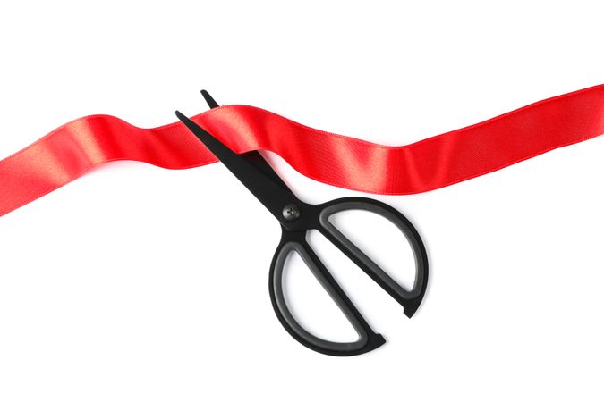 Red ribbon and scissors isolated on blank background. Gift concept