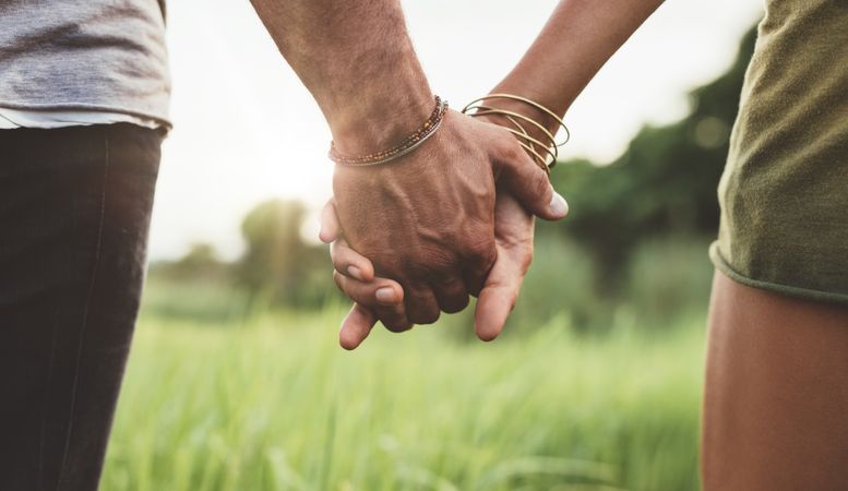 Young couple walking through meadow hand in hand