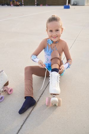 Content girl in sportswear putting on roller skate
