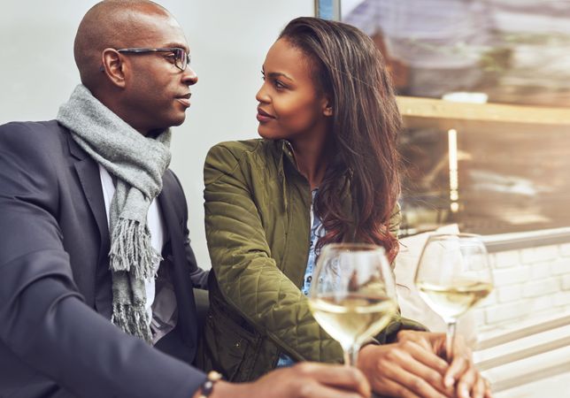 Black couple looking into each others eyes with wine in hand