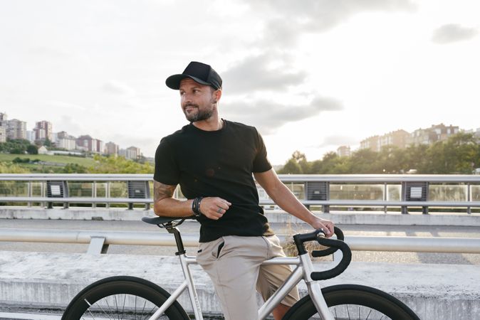 Cheerful man with bicycle standing on footbridge
