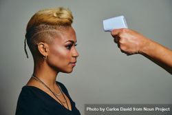 Black woman with short blonde hair having her temperature checked bDnOr5