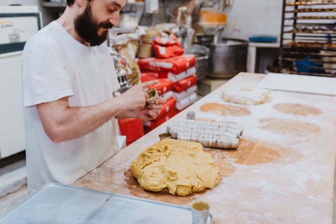 Bearded confectioner putting dough into cup