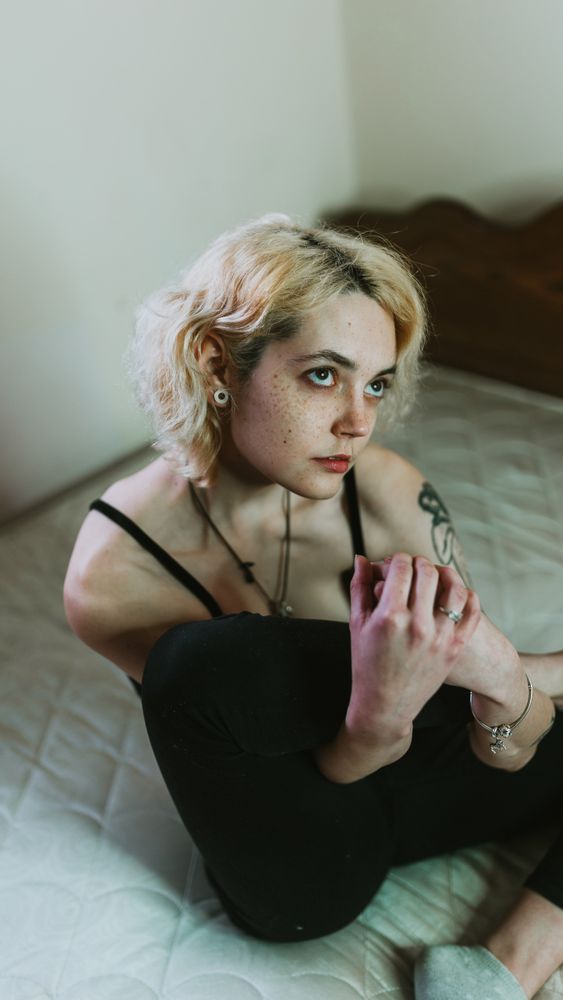 thoughtful young woman sitting in bed and looking away