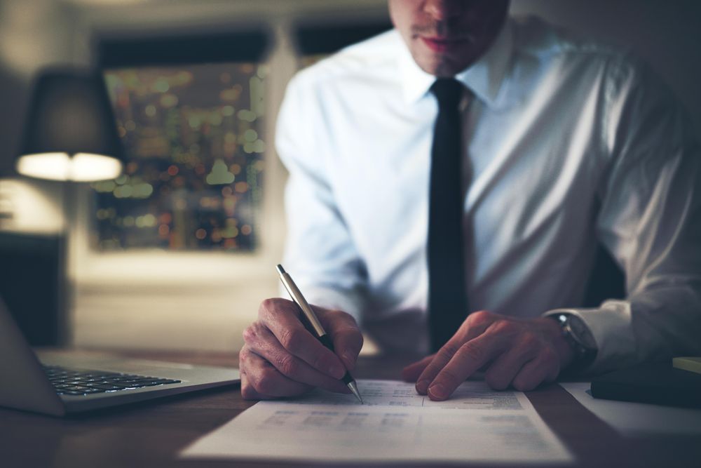 Man in shirt and tie looking over documents in the evening