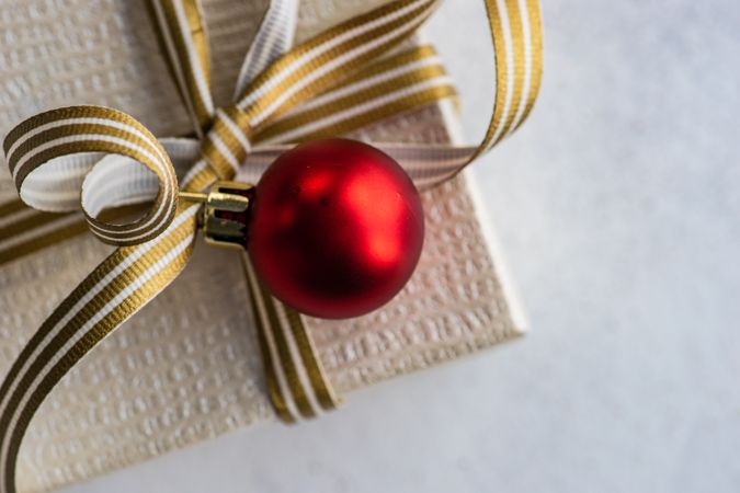 Top view of Christmas present with gold ribbon and red bauble