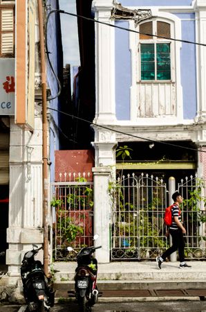 Man walking on sidewalk beside a house in George Town, Penang, Malaysia