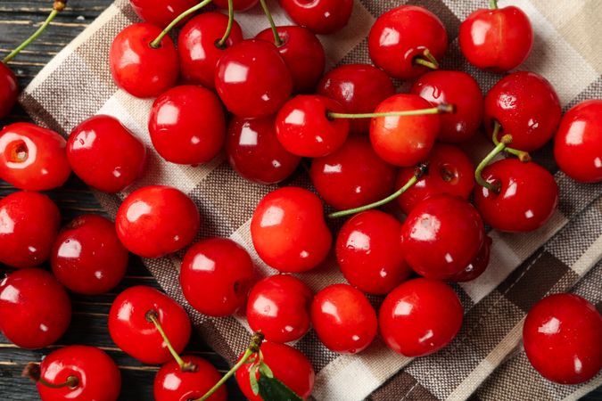 Towel with cherry on wooden background, top view