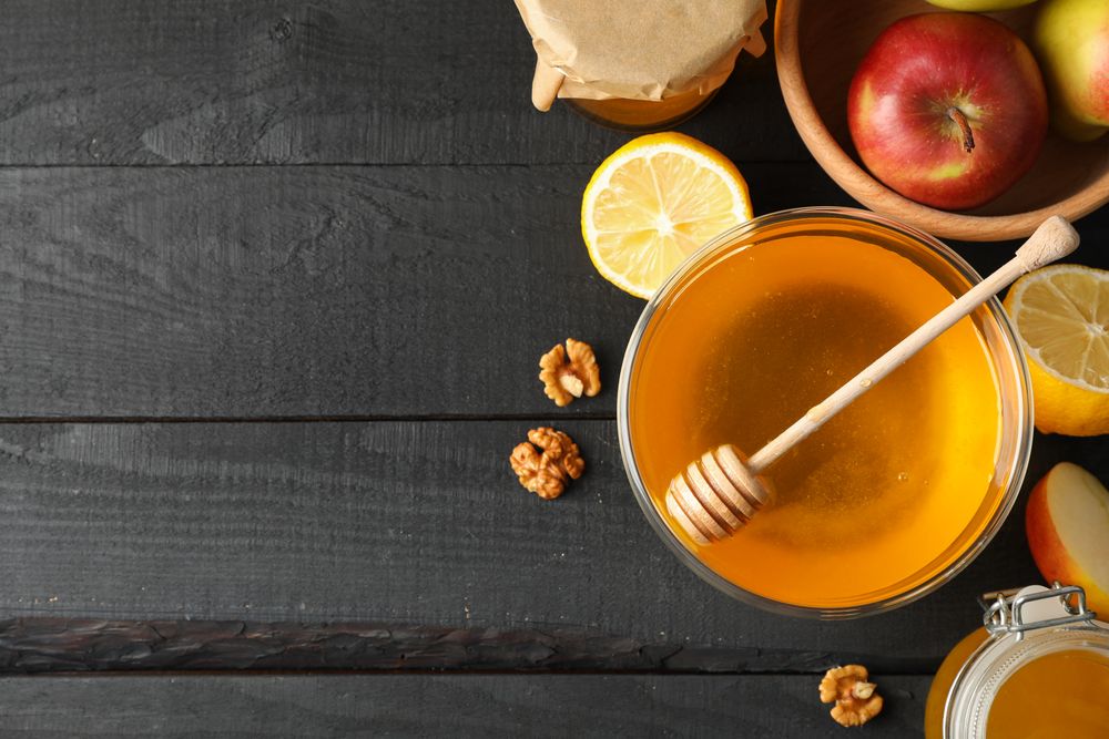 Honey, dipper, walnut and fruits on wooden background, top view