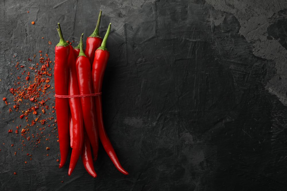 Chilli peppers on dark background, top view