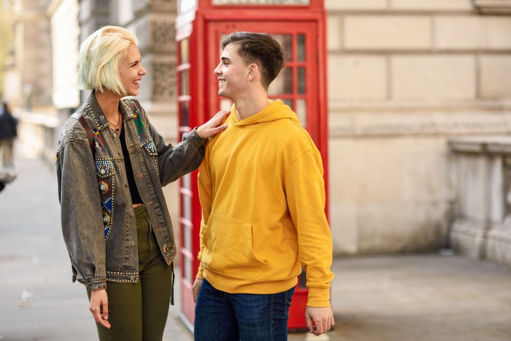 Male and female looking at each other in front of a phone booth