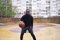 Young Black Man Dribbling Basketball Outdoors.