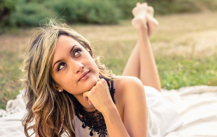 Romantic woman thinking lying down outdoors