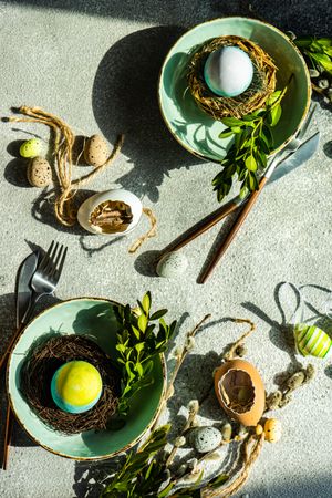 Easter table setting with blue egg in a nest in two bowls on table