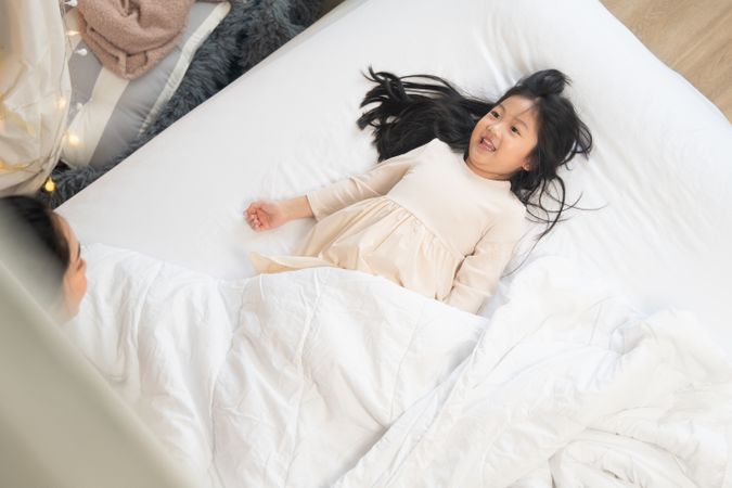 Asian happy girl in white dress lying on bed.