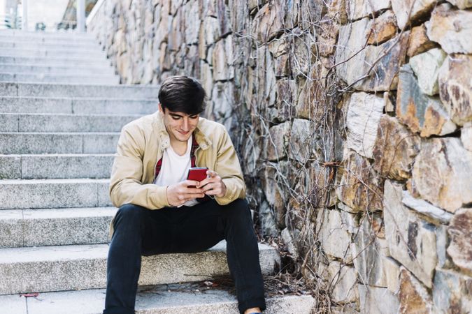 Man texting while sitting on outdoor stairs