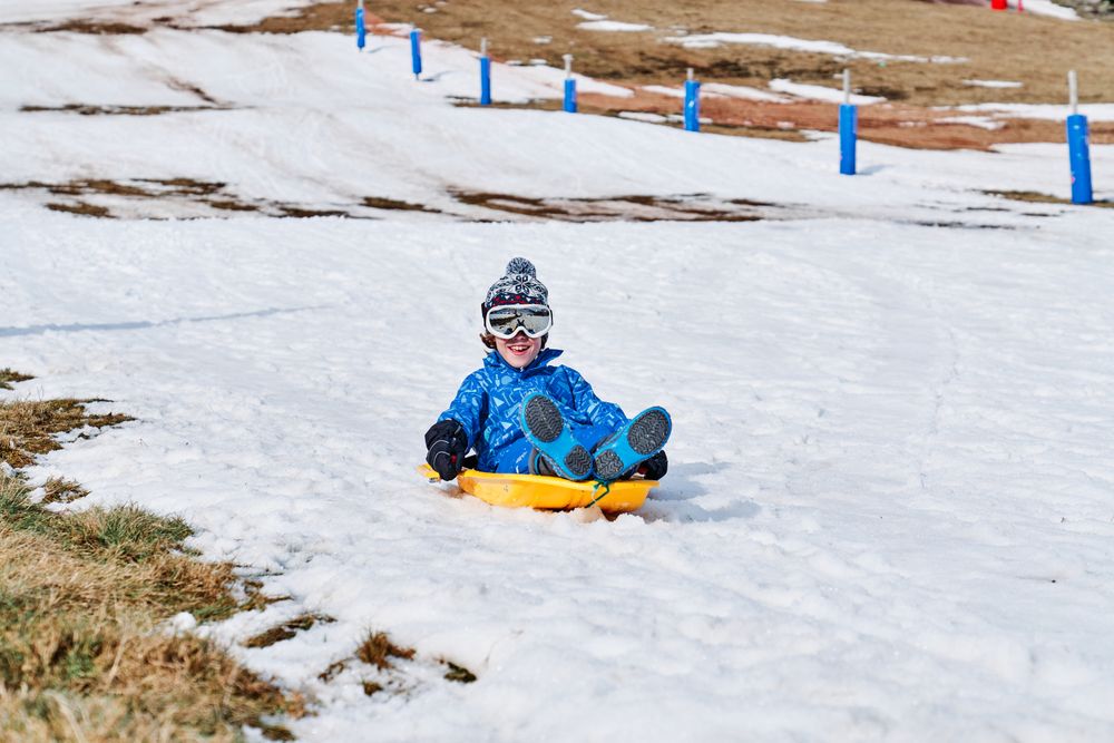 Positive boy sliding down snowy slope
