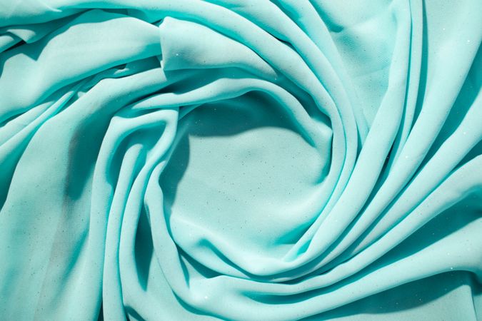 Spiral Twisted Turquoise wavy crumpled fabric with little sparkling dust and copy space in center, texture and  background.