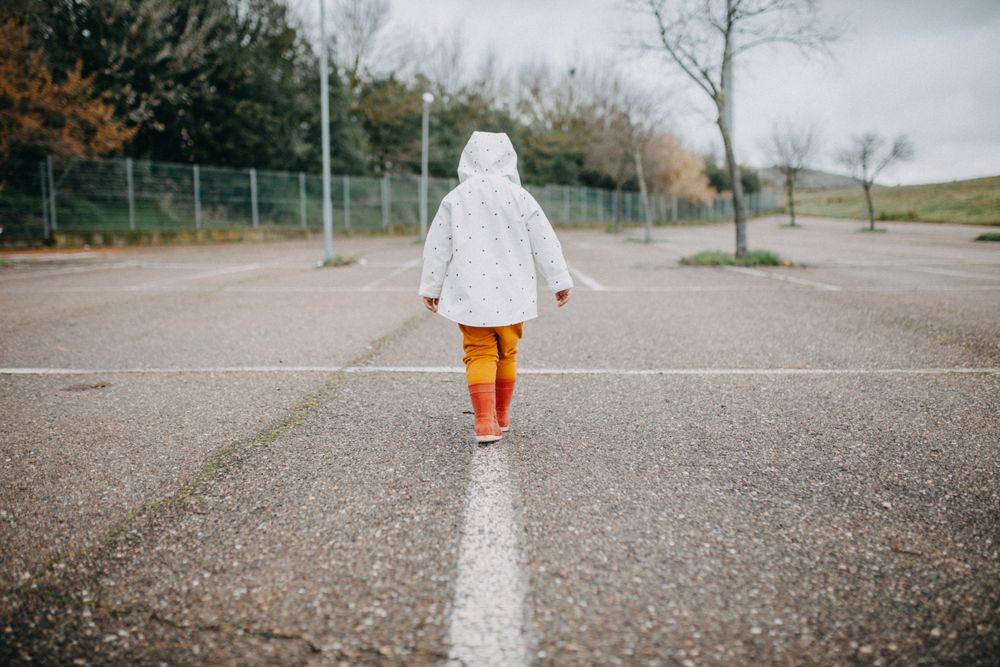 Child balancing on painted white stripe on pavement