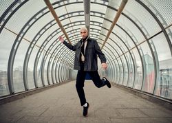 Fashionable young man in motion dancing in public walkway