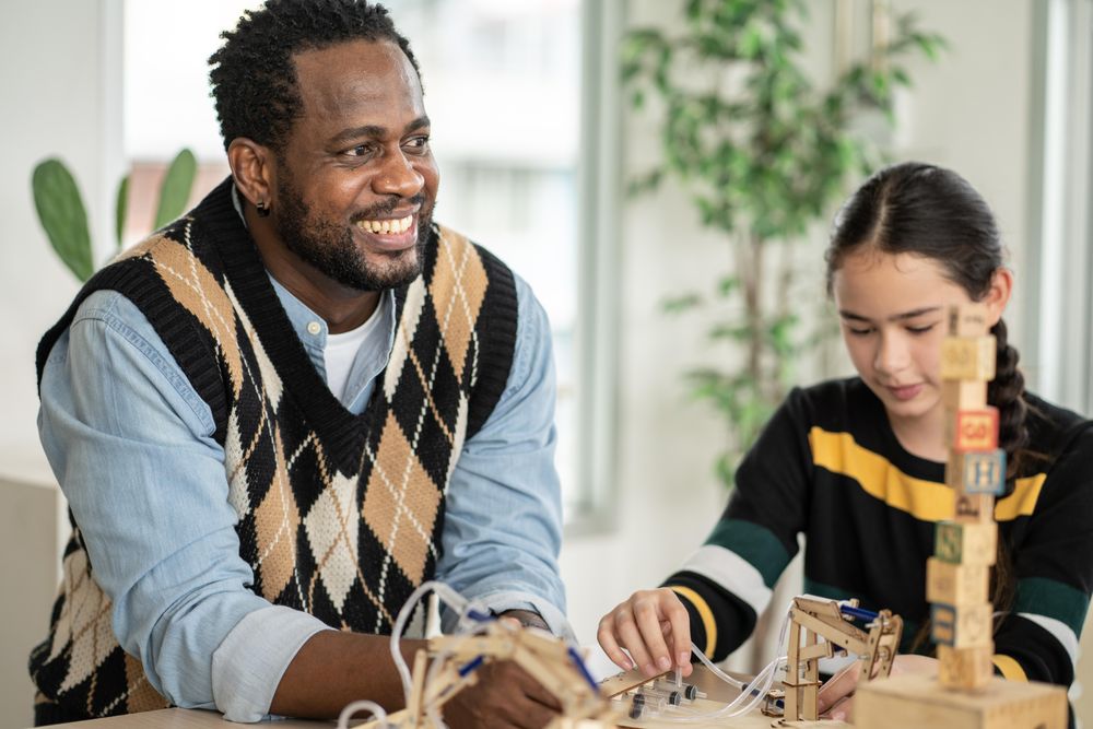 Happy teacher working with wooden blocks in his classroom