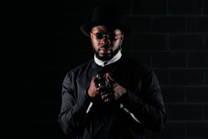 Stylish Black man looking at camera in black studio