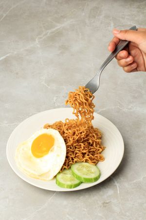 Person lifting noodles with fork