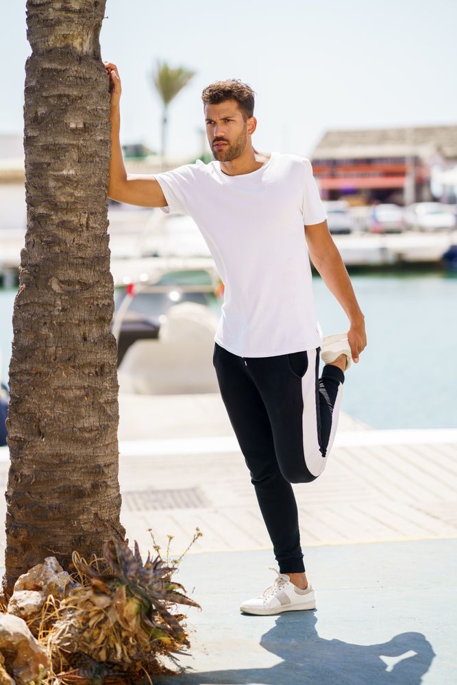Man balancing next to palm tree as he stretches his legs
