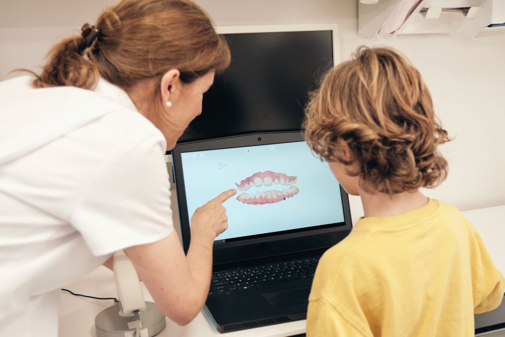 Female dentist explaining 3D teeth scan to faceless boy