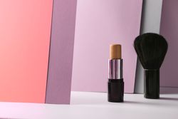 Concealer stick and make up brush on modern background