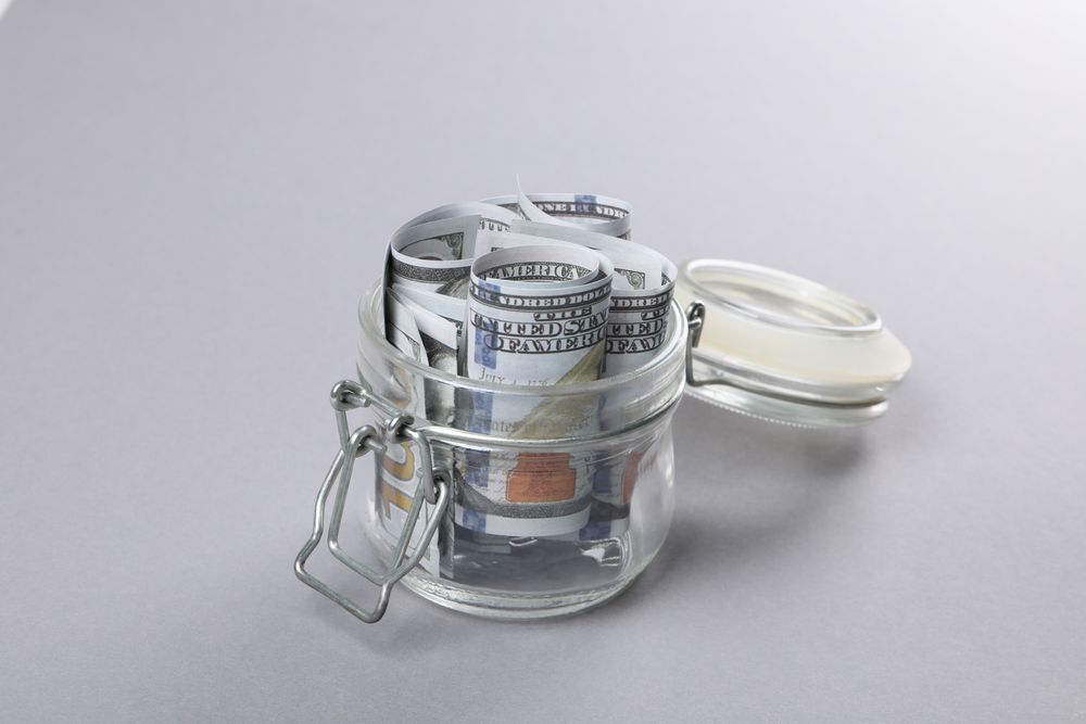 Jar with Dollar bills on gray background