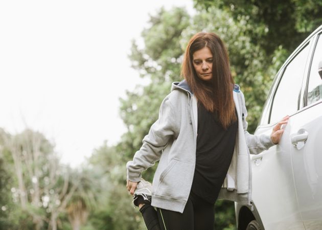 Woman stretching near car in park