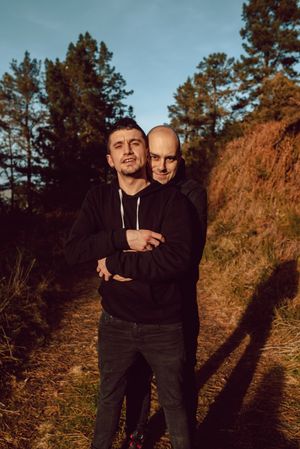 Smiling men hugging on path in park