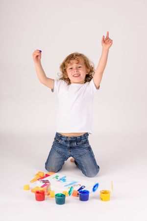Excited boy near colorful paints