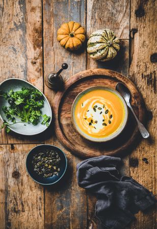 Pumpkin soup with cream, garnished, and squash, on wooden table