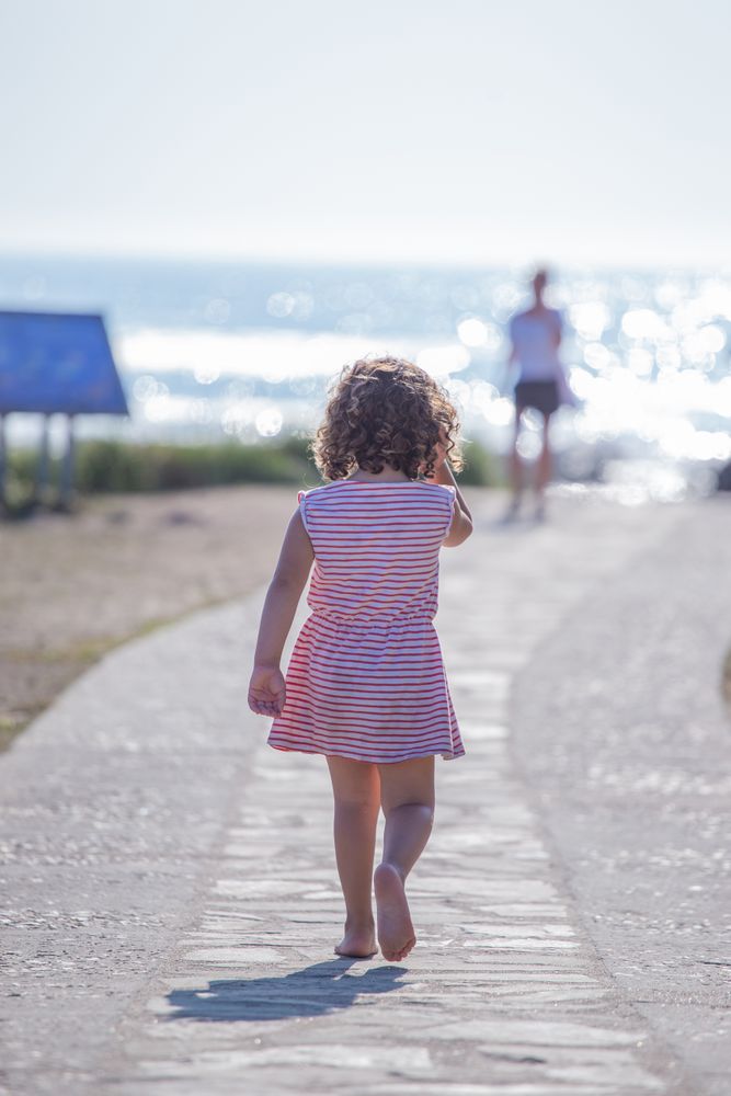 Little girl walking towards mother on seashore