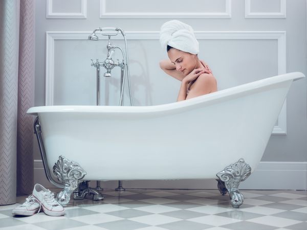 Young woman with towel on head in bathtub