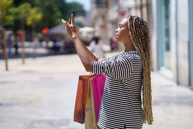 Female holding up mobile phone taking a picture on street