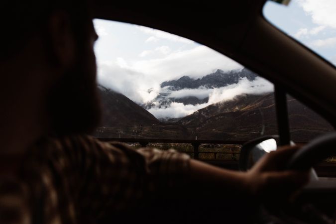 Powerful mountains and cloudy sky view from window of car