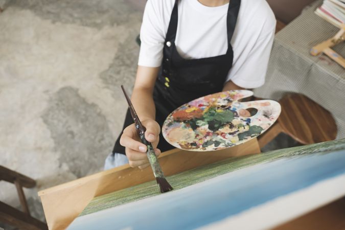 Young Asian female artist painting on canvas doing art projects on her studio.