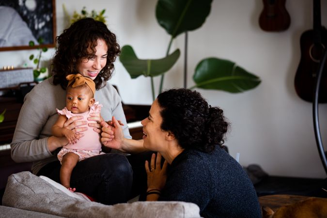 Two woman playing with baby at home