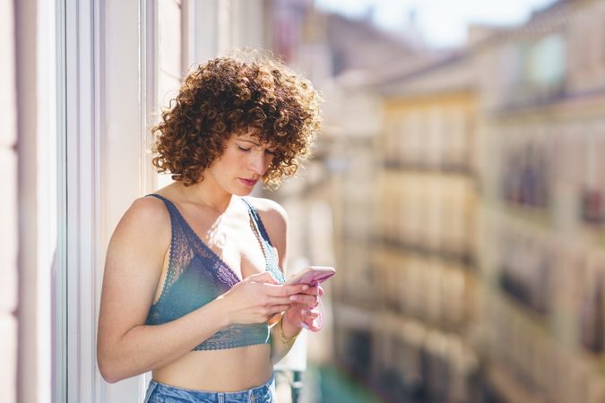 Woman lounging outside checking phone on apartment patio