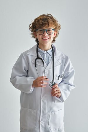 Cheerful boy doctor in medical uniform and eyewear