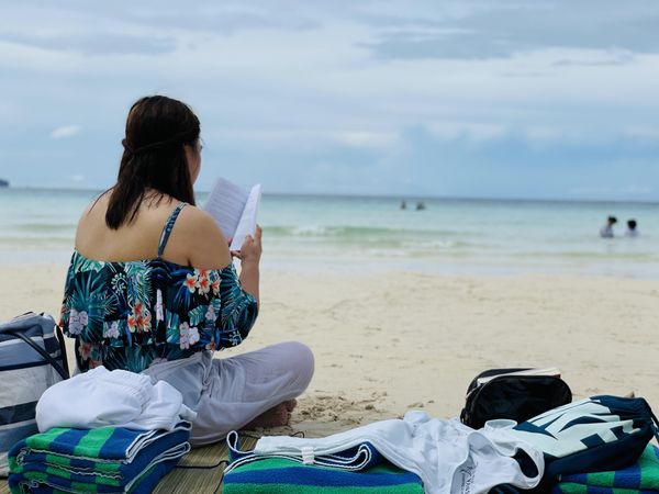 Woman sitting by the beach reading book