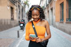 Portrait of a young Black woman using smartphone in the street