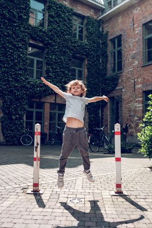 Excited boy jumping near aged building